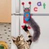 chat qui joue avec le jouet pour chat connects magnicat kong fixé sur le réfrigérateur