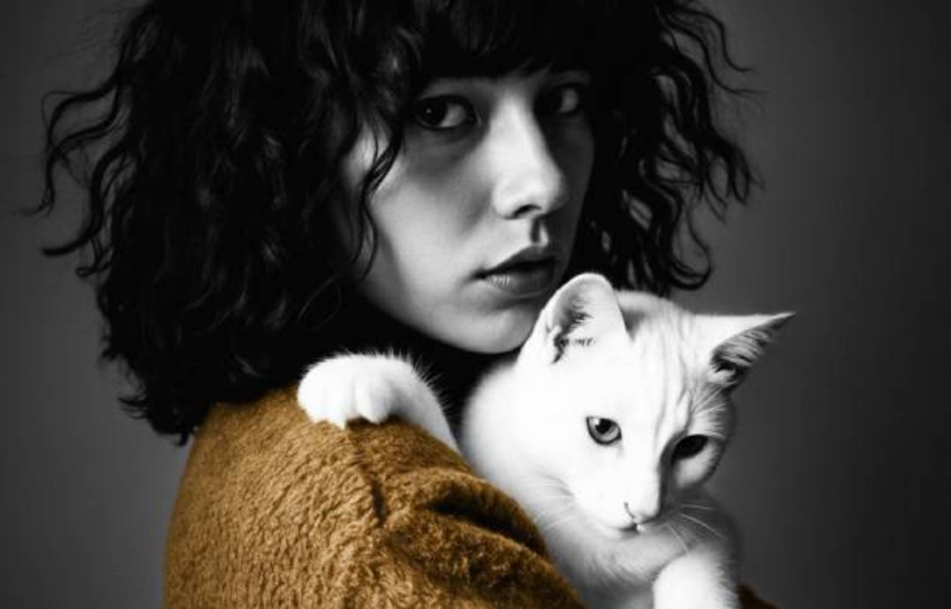 femme avec un pull jaune qui porte un chat blanc dans les bras